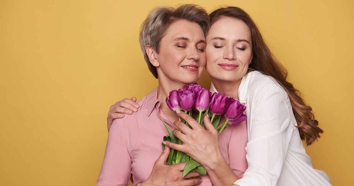 Beautiful Caucasian girl is hugging her mother while posing for camera